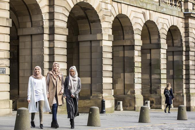 Three young women walking past Edinburgh City Chambers in the High Street, Royal Mile, Edinburgh, Scotland.