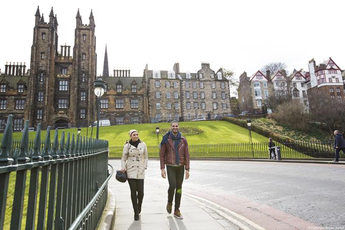  Young couple walking along an iron fence outside the Scottish National Gallery, Edinburgh, Scotland.