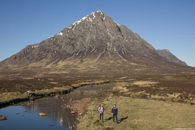 Two men hiking along the River Etive in the Scottish Highlands, with Buachaille Etive Mor in the distance.