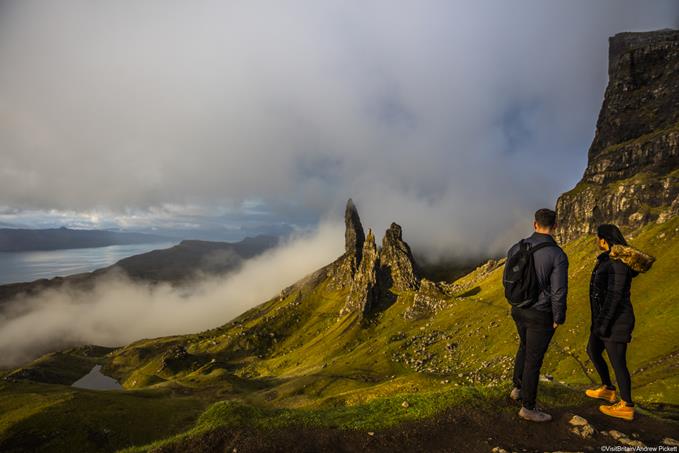 Couple standing near basalt pinnacles called The Old Man Of Storr on the Trotternish Peninsula overlooking the Sound of Raasay, Isle of Skye, Scotland, UK.