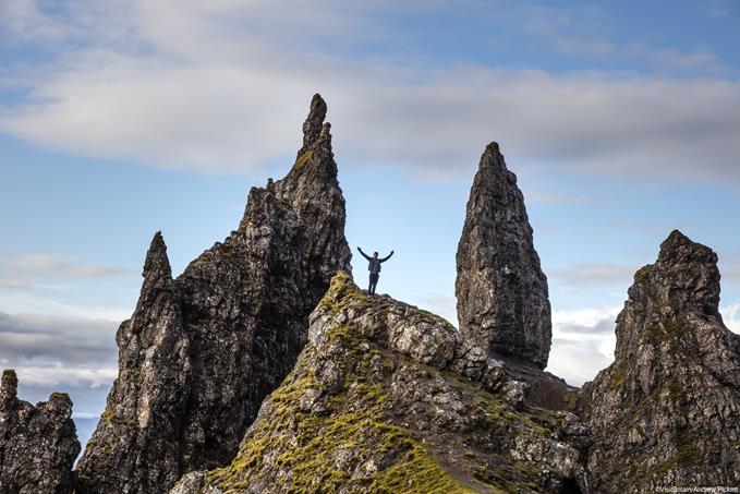Man standing at basalt pinnacles called The Old Man Of Storr on the Trotternish Peninsula overlooking the Sound of Raasay, Isle of Skye, Scotland, UK.